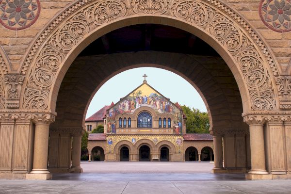 A detailed archway frames a colorful, decorated building with a cross on top, creating a symmetrical view of architectural beauty.