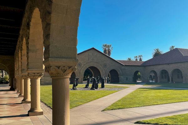 A courtyard with arched pathways, grassy areas, and a group of statues.