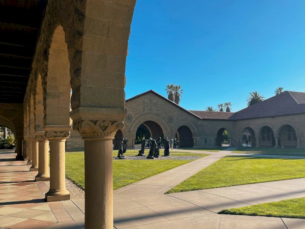 A courtyard with arched pathways, grassy areas, and a group of statues.