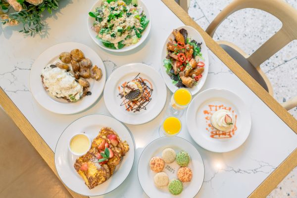 A tabletop with various dishes, including salads, desserts, and drinks, creatively presented with colorful garnishes and sauces.
