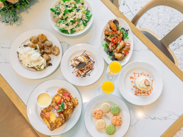 A tabletop with various dishes, including salads, desserts, and drinks, creatively presented with colorful garnishes and sauces.