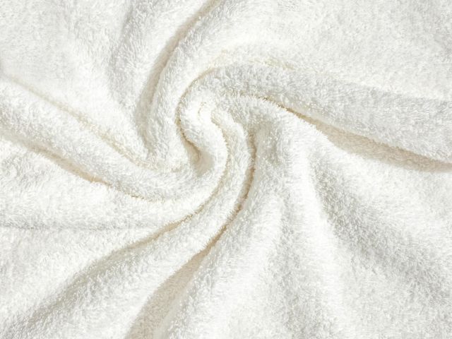 The image shows a close-up of a soft, white, fluffy fabric, possibly a towel or blanket, with a swirl pattern in the center.