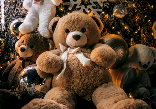 A cozy scene with oversized teddy bears among festive lights and ornaments, cozying up for a holiday display.
