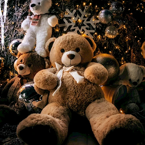 A cozy scene with oversized teddy bears among festive lights and ornaments, cozying up for a holiday display.