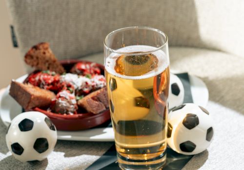 A pint of beer on a table with soccer balls and a snack plate of pizza and chips&mdash;ready for game time.