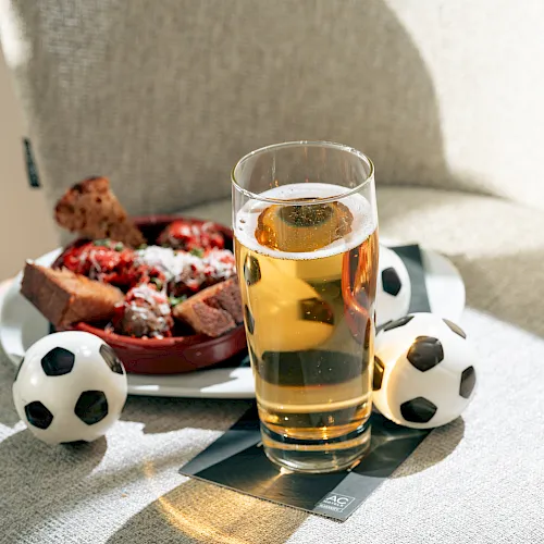 A pint of beer on a table with soccer balls and a snack plate of pizza and chips&mdash;ready for game time.